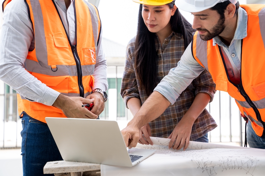 engineerandarchitectdiscussingbuildingplanatconstructionsitegroupof