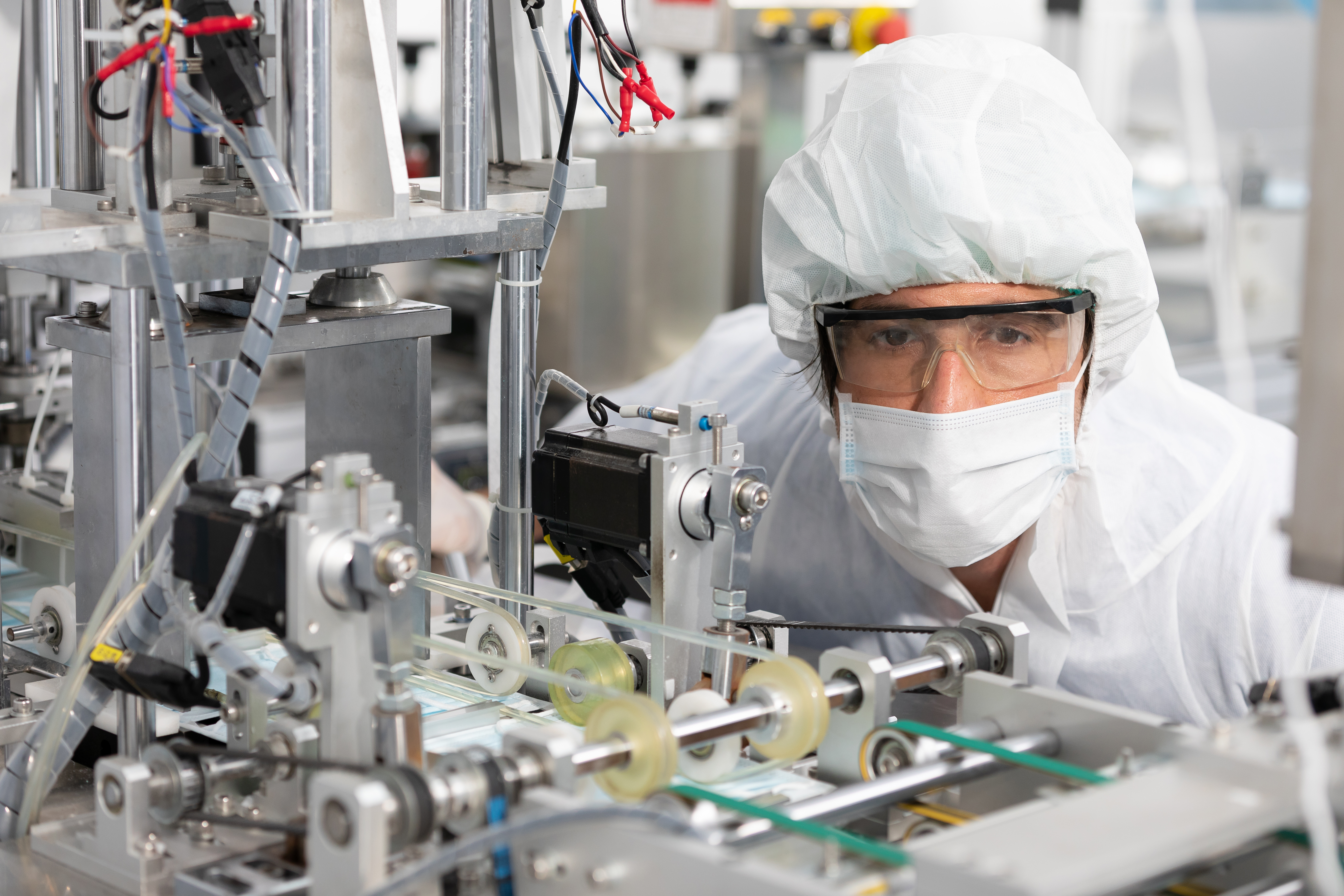 male engineers wearing personal protective equipment uniform(PPE) and medical face mask, checking machine in laboratory