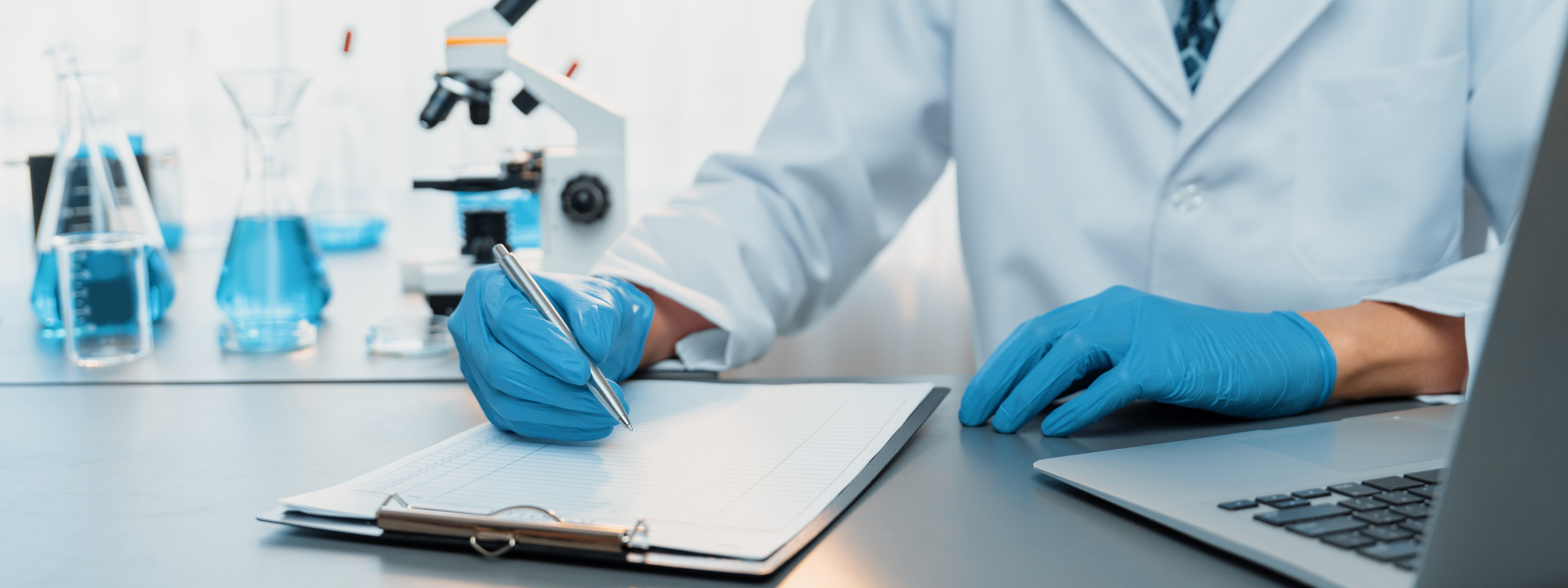 Closeup hand recording clinical data result after conducting chemical experiment in medical laboratory for vaccine drug or antibiotic. Scientific chemistry lab and medicine research concept. Neoteric